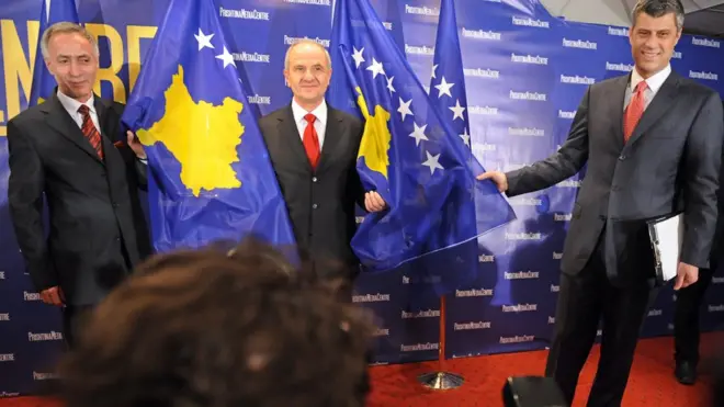 Hašim Tači prezentuje novu zastavu Kosova (desno), zajedno sa predsednikom Kosova Fatmirom Sejdiuom (u sredini) i predsednikom Skupštine Kosova Jakupom Krasnićijem (levo)
