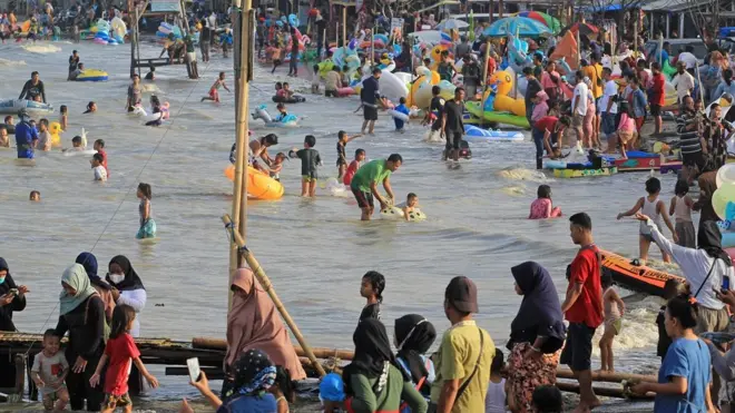 Pengunjung menikmati suasana liburan di pantai Karangsong, Indramayu, Jawa Barat, Jumat (14/5/2021).