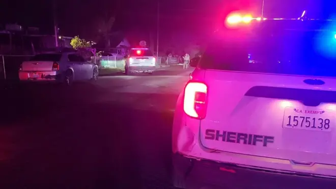 Police cars outside the home where six people were shot in Goshen, California