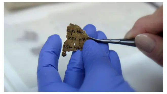 A worker of the Israeli Antiquity Authority sews fragments of the Dead Sea scrolls which includes biblical verses in a preservation laboratory of the Israel Museum in Jerusalem.