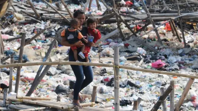 Foto ilustrasi: Ibu dan anak melintasi jembatan bambu di kawasan kumuh pantai, Cilincing, Jakarta pada 21 November 2019. Keterbatasan tempat tinggal membaut sejumlah warga tinggal di kawasan yang dipenuhi sampah itu.