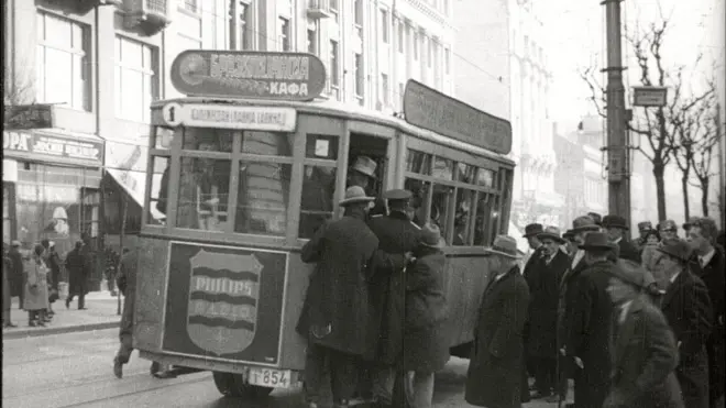 Путници покушавају да се попну у пун транвај, сцена из филма