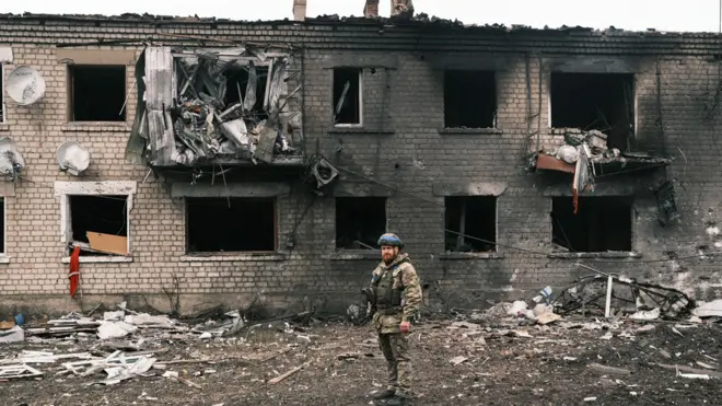 A Ukrainian police officer inspects a damaged building in Vovchansk