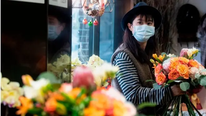 Florist Zhao Yuanyuan wearing a protective face mask as she arranges flowers in her shop in Shanghai