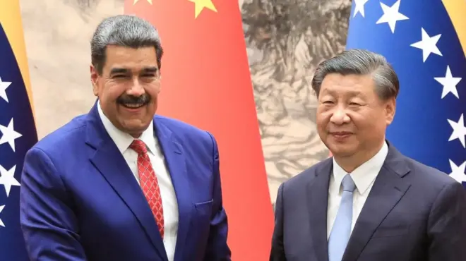 Venezuelan president Nicolás Maduro (L) and Chinese president Xi Jinping shake hands and smile in front of Venezuelan and Chinese flags at the palace in Beijing in 2023.