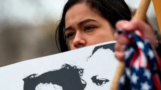 પોસ્ટર સાથે ઊભેલી યુવતી