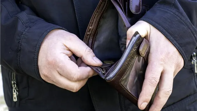 Мужчина считает монеты в кошельке