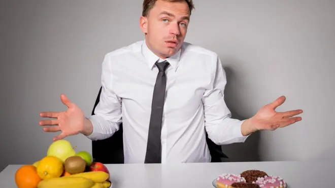 Hombre eligiendo entre frutas bollería.