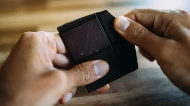 Homem quebrando com a mão pedaçoppp pokerchocolate