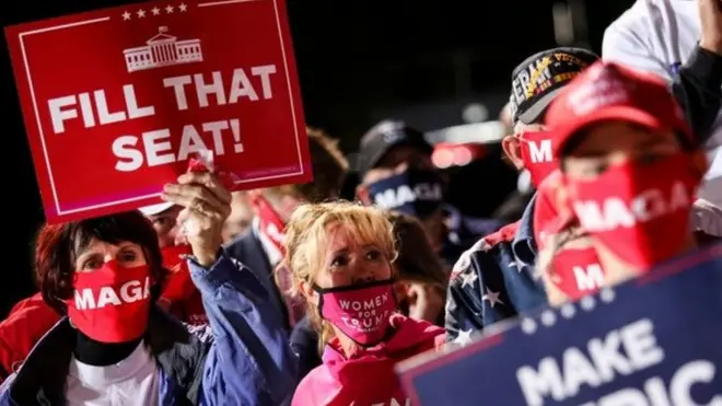 Trump supporters hold a sign telling Trump to fill the seat
