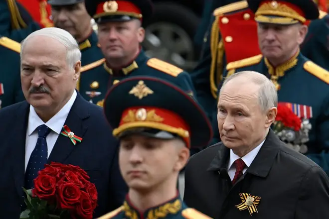 Лукашенко і Путін у чорних плащах стоять на параді в оточені військових