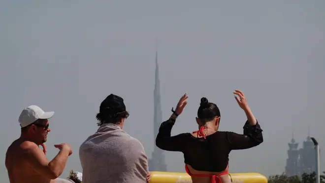 Люди отдыхают на пляже Кайт-Бич на фоне небоскреба Бурдж-Халифа после иранской атаки, последовавшей за ударами США и Израиля по Ирану