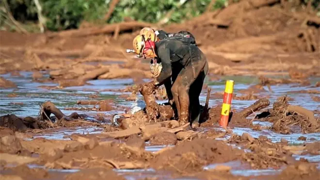 Sejumlah anggota regu penyelamat berupaya menarik tubuh seseorang dari timbunan lumpur setelah bendungan jebol di dekat Kota Brumadinho, Brasil.