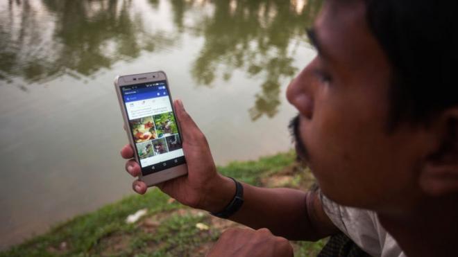 A Rohingya ethnic minority man looking at Facebook on his cell phone