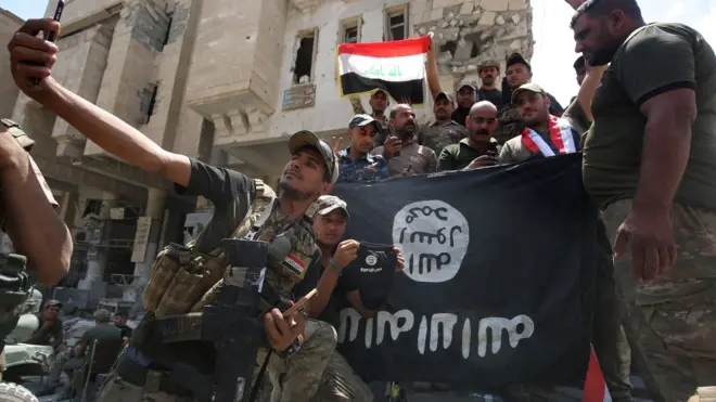 عراقي سرتېري د داعش بیرغ لرې کوي او خپل لګوي.