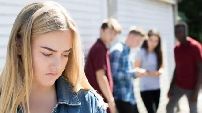Une fille mal à l'aise parce que les autres garçons la regardent.
