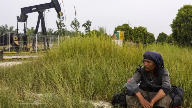 Seorang warga beristirahat di dekat monumen pompa angguk minyak tertua di daerah Minas, Blok Rokan, Riau, Rabu (01/8).