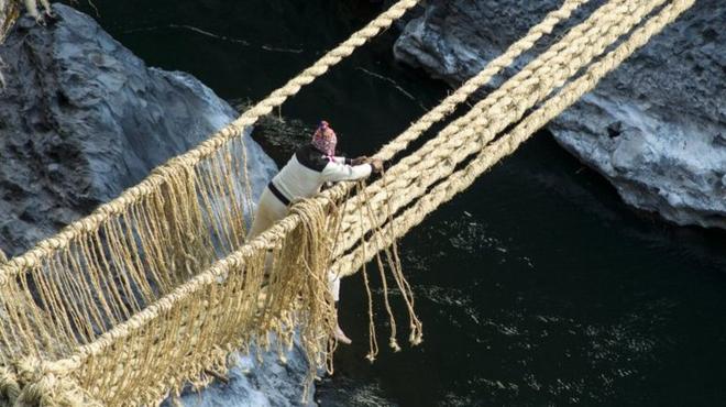 A man ties the ropes that form handrails