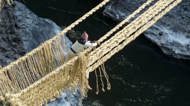 A man ties the ropes that form handrails