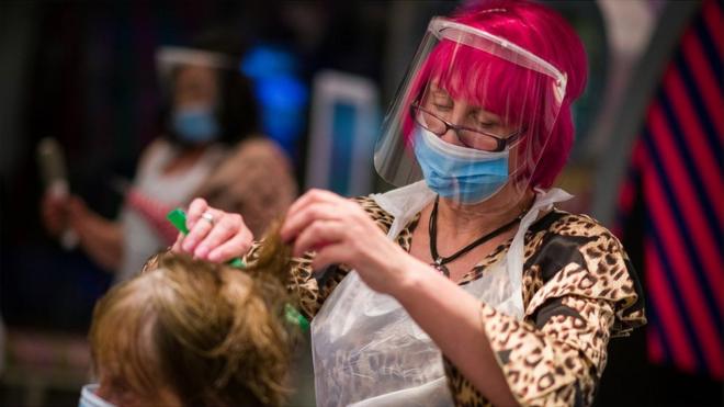 Hair salon owner Carole Rickaby cuts a customer's hair at Tusk Hair stylists in Camden just after midnight on 4 July