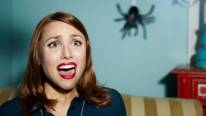 A woman afraid of a spider hanging from a thread
