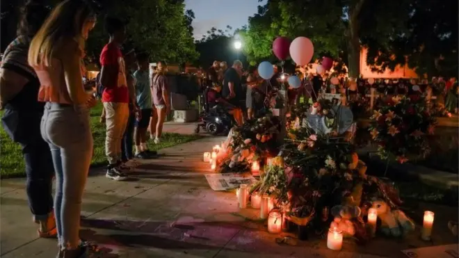 People stand in prayer in front of memorial crosses, for the children who died in the mass shooting at Robb Elementary School, in Uvalde, Texas, U.S. May 27, 2022