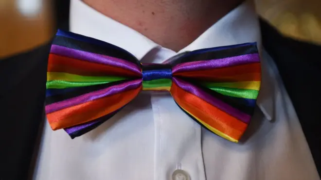 شاب يرتدي رابطة عنق بألوان علم المثلية الجنسية