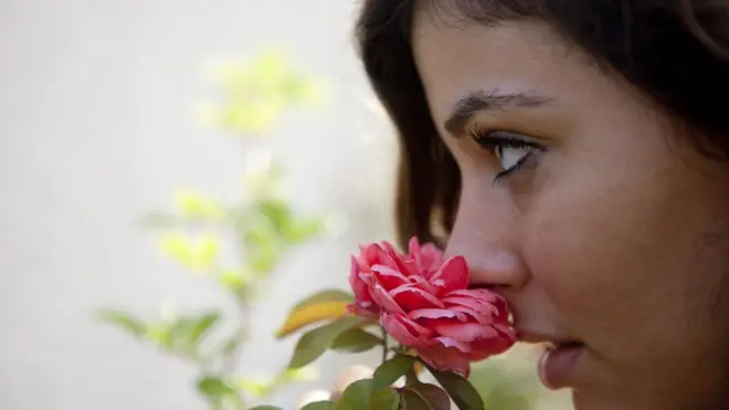 పువ్వు వాసన చూస్తున్న మహిళ