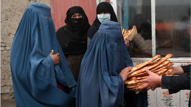 Mulheres vestindo burca recebem pão grátis distribuído como parte da campanha Salve os Afegãos da Fome em Cabul (18 de janeiro de 2022.)