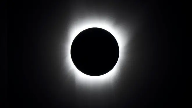 In a total solar eclipse, the Sun is completely covered by the Moon and only a white halo can be seen around the black disc