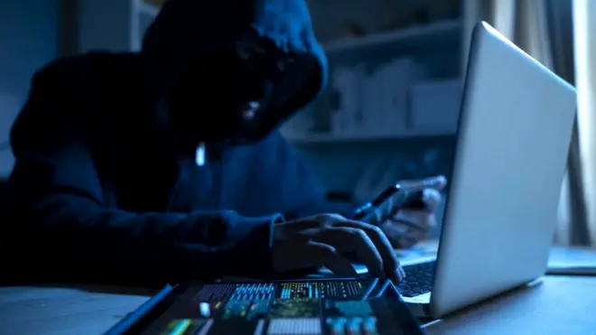 Hooded man at a computer