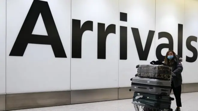 A passenger arrives wearing a mask at Terminal 4, Heathrow Airport, London