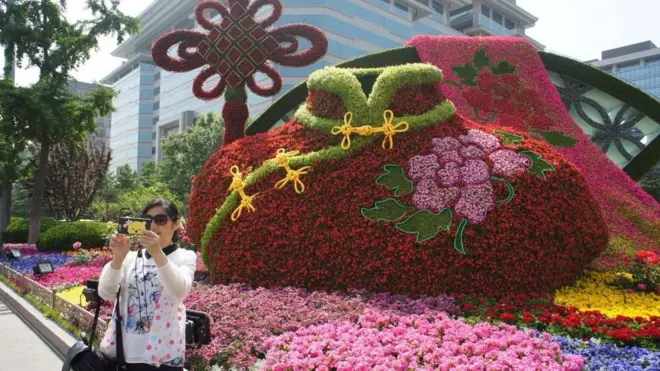 Chụp ảnh trước hình hoa bài trí theo chủ đề Vành đai và Con đường ở Bắc Kinh