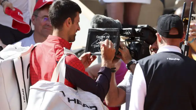Novak Djokovic writing a message on a camera lens