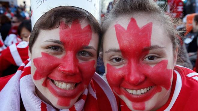 Personas con la bandera de Canadá pintada en sus rostros.