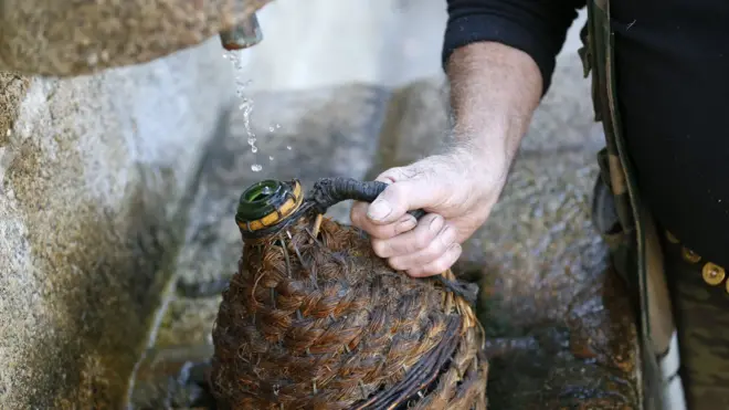 رجل يملأ زجاجة من صنبور مياه ضعيفة