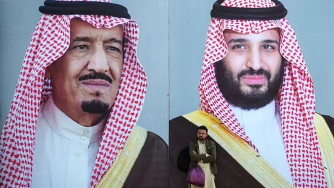 A Pakistani man waits for transport in front of billboards showing portraits of Saudi Arabian Crown Prince Mohammed bin Salman (R) and his father and Saudi Arabia"s King Salman bin Abdulaziz displayed on a street ahead of the prince"s arrival in Islamabad on February 15, 2019