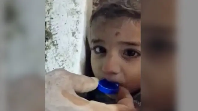 رجال الإنقاذ يقدمون الماء لطفل عالق تحت الأنقاض