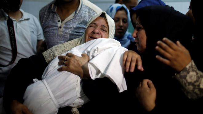 A relative mourns as she carries the body of 8-month-old Palestinian infant Laila al-Ghandour