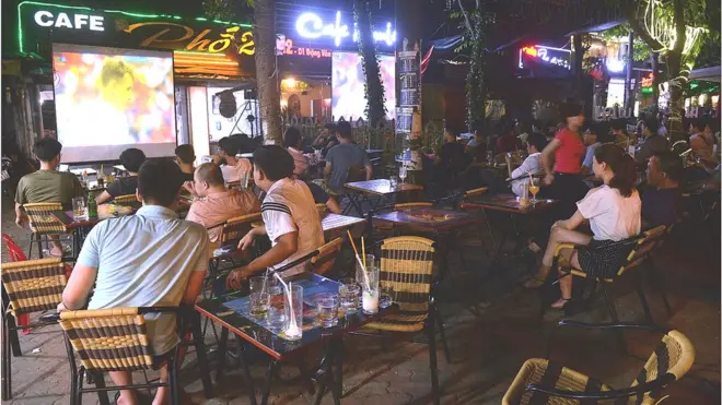Khán giả hâm mộ đang theo dõi bóng đá quốc tế qua một màn hình trên phố