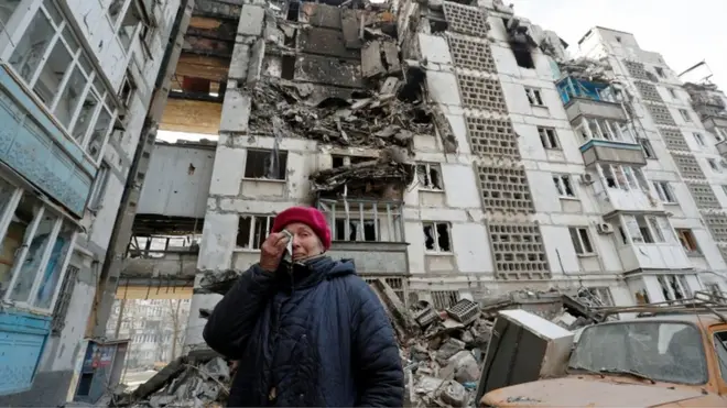 Valentina Demura, 70, bereaksi di sebelah gedung apartemennya, yang hancur akibat konflik Ukraina-Rusia di kota pelabuhan Mariupol, 27 Maret 2022.