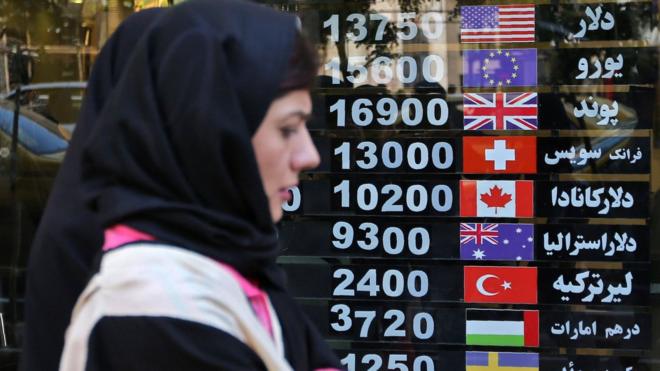 Iranians walk past a foreign exchange shop in Tehran on 22 April 2019
