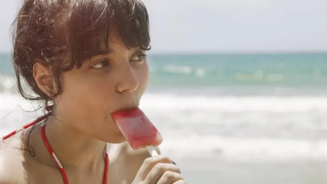 Дівчина їсть морозиво на пляжі