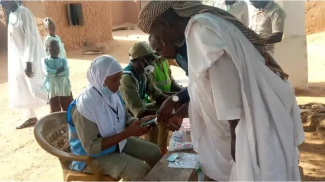 Awọn oṣiṣẹ ajọ INEC pẹlu oludibo kan.