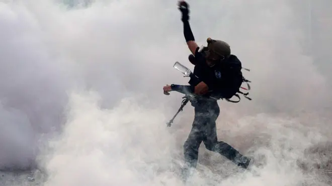 Seorang peserta unjuk rasa melemparkan batu ke arah polisi sebagai balasan atas tembakan gas air mata di Wong Tai Sin, Hong Kong.