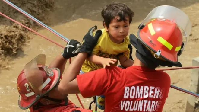 Bomberos y voluntarios rescatando a residentes de Huachipa, un poblado distrito al este de Lima.