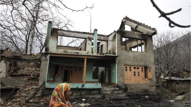 ترال کی ایک خاتون اپنے جل کر خاکستر ہوئے آشیانے کے سامنے بے بسی کی تصویر بنے کھڑی ہے۔