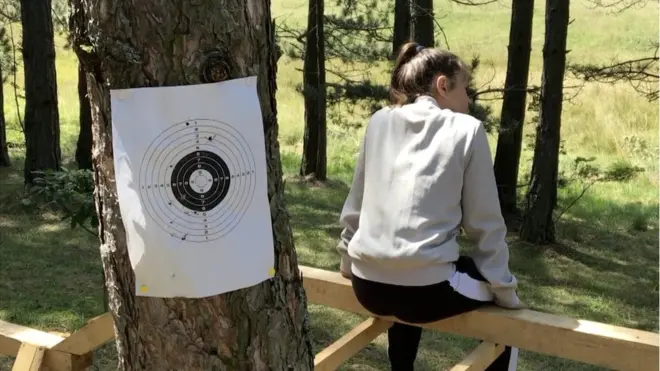 Девојчица седи поред дрвета на коме је мета