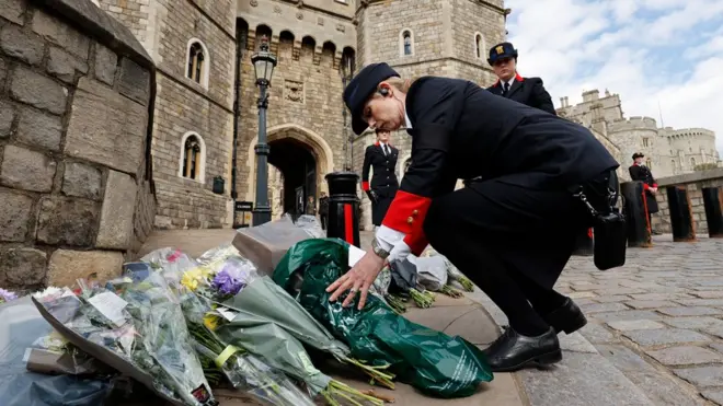 Wardens of the Castle move floral tributes to the side of the driveway at the Henry VIII Gate of Windsor Castle