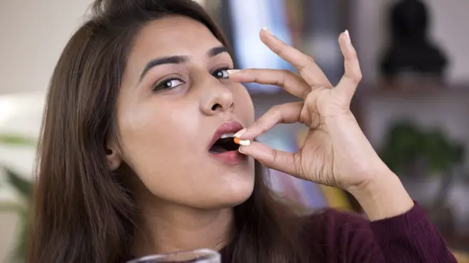 టాబ్లెట్ వేసుకుంటున్న భారతీయ మహిళ